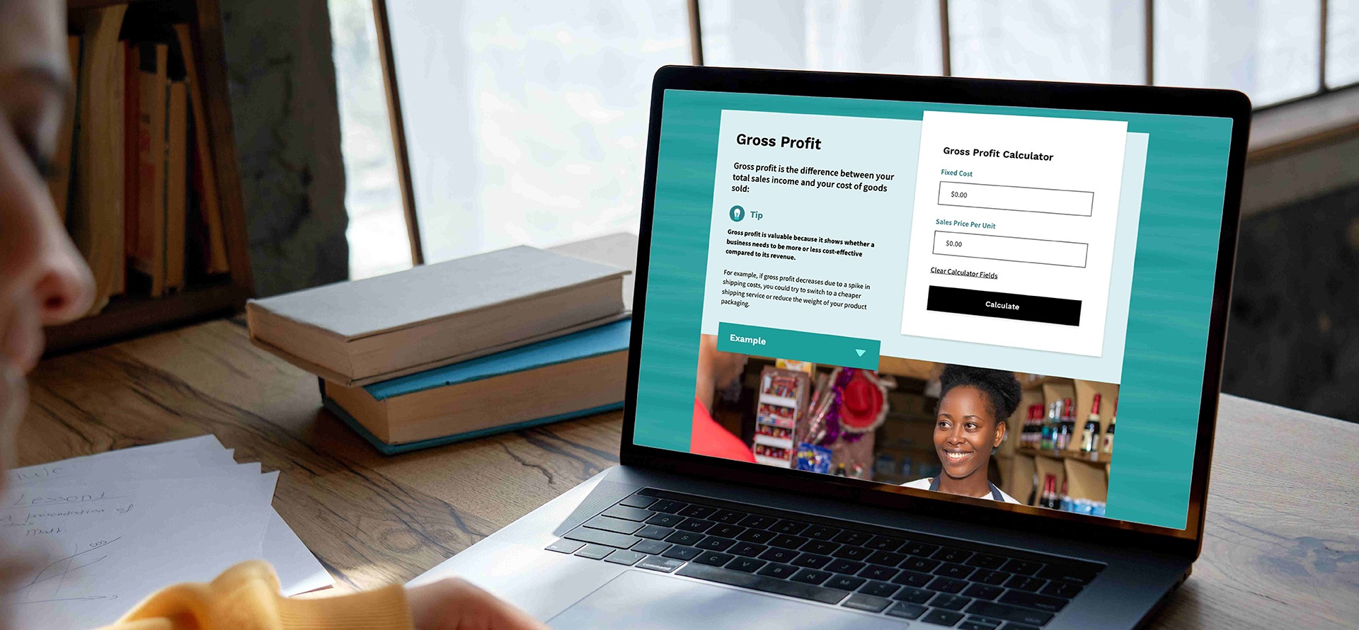 Valley Heartland Business Calculator page showing on a laptop, sitting on a desk in front of a smiling woman.